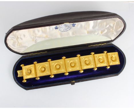 A 19th century Etruscan Revival yellow metal bracelet, the seven square shaped panels with central stylised flowerhead detail