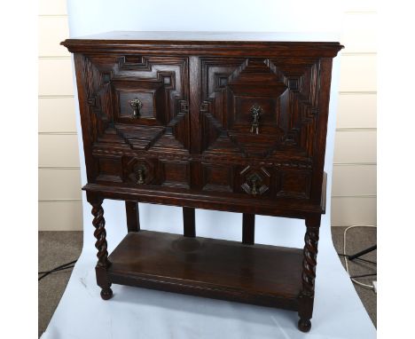 An oak cabinet on stand, early 20th century, with fielded panelled doors, frieze drawers and pot board below, width 99cm, hei
