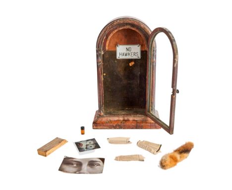 A wooden curio cabinet with glass door from Dennis Hopper's residence in Taos, New Mexico. The cabinet contains the following