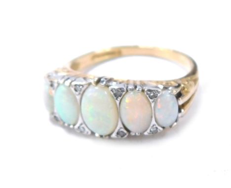 A 9ct gold opal and diamond dress ring, the setting set with five oval opals and eight tiny diamonds, with scroll and ribbed 