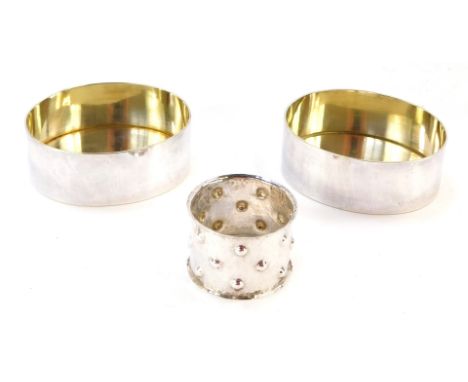 A German napkin ring, with hammered decoration, white metal, stamped 835, together with a pair of oval containers, with gilt 