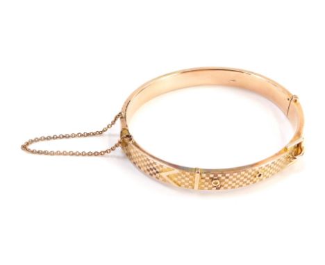 A 9ct rose gold hinged bangle, the half hinged design with hatched detail and buckle, 6cm wide, with safety chain, 16.7g all 