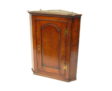 An 18thC oak hanging corner cupboard, with single trunk door with panel section, with brass hinges and escutcheon, 92cm high,