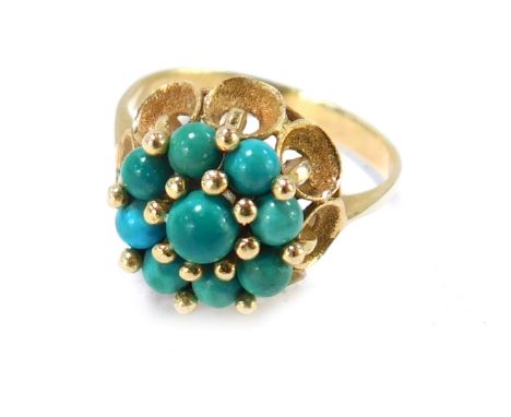 A turquoise dress ring, the turquoise cluster on fluted bark effect petal detail, on yellow metal band, unmarked, size O½, 4.