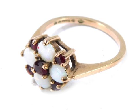 A 9ct gold opal and garnet cluster ring, with four circular cut opals, an arrangement of garnets in claw setting on raised ba