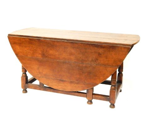 An early 18thC oak gate leg table, with oval top, two drop leaves on a turned  base, 76cm high, 159cm wide, 165cm deep.