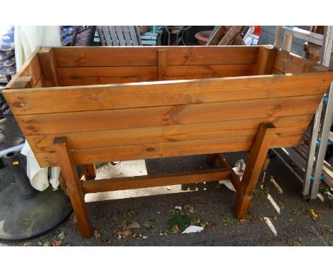 A modern raised wooden planter, on a trestle base, 81cm high, 120cm wide, 51cm deep.