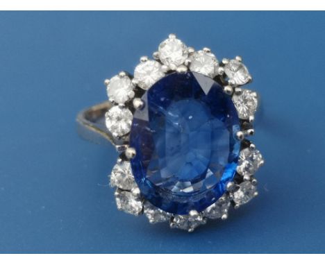 A modern sapphire &amp; diamond set cluster ring, the oval claw set sapphire weighing approximately 4 carats, on 14ct white g