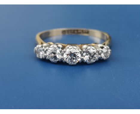 A five stone graduated claw set diamond ring, the central stone weighing approximately 0.20 carat - '18ct &amp; Plat'.  Finge