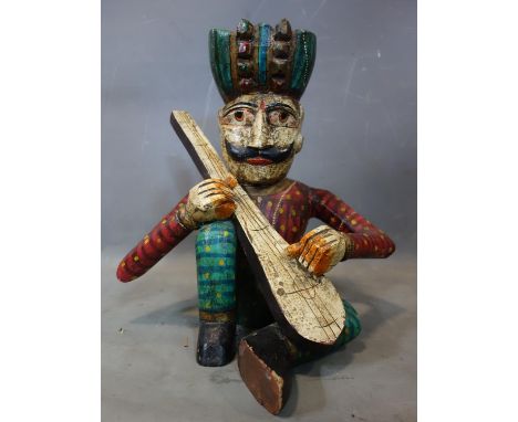 A carved wooden figure of a seated man with a turban playing the lute, H.45cm 