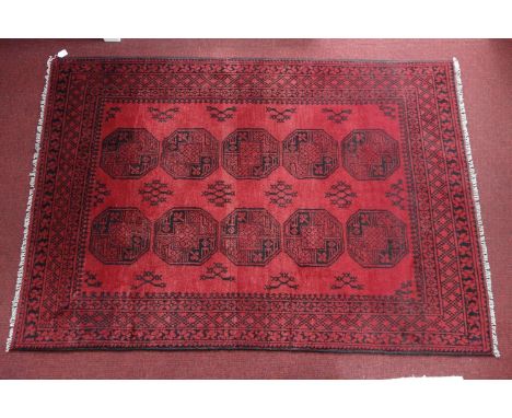 A Turkoman carpet with repeating goul motifs, on a red ground, contained by geometric borders, 240 x 167cm 