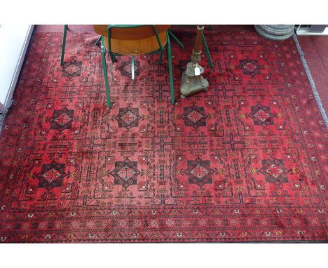 A Khan Mohammadi Afghan carpet, with 12 geometric motifs, on a red ground, contained by geometric borders, 240 x 167cm 