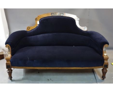 A Victorian Aesthetic walnut sofa, with boxwood and ebony inlay and blue velour upholstery, raised on turned legs and castors