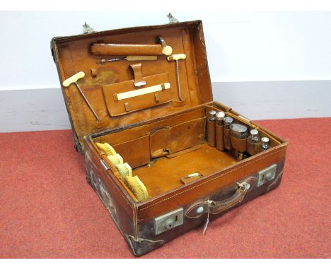 An Early XX Century Leather Bound Suitcase, the interior fitted with four ivorine backed brushes, pair of boot pulls, assorte