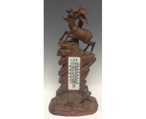 A large Black Forest table thermometer, carved as a deer atop a rocky outcrop, another at rest below, mercury thermometer, 36