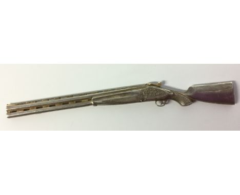 An unusual novelty white metal miniature or toy, as a double-barrel over-and-under shotgun, chased throughout with a foliate 