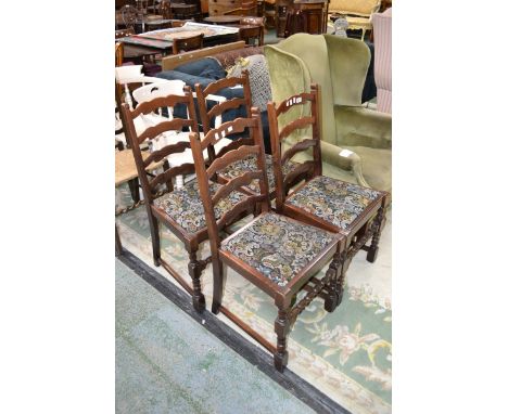 A set of four oak dining chairs with ladder backs and raffia seats.