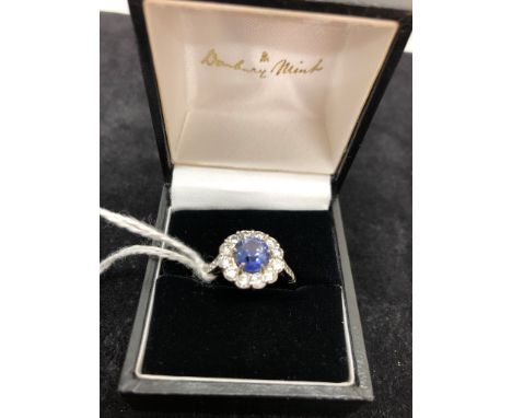 A diamond and sapphire daisy ring, the large light blue claw set sapphire surrounded by 12 diamonds and three each to the sho