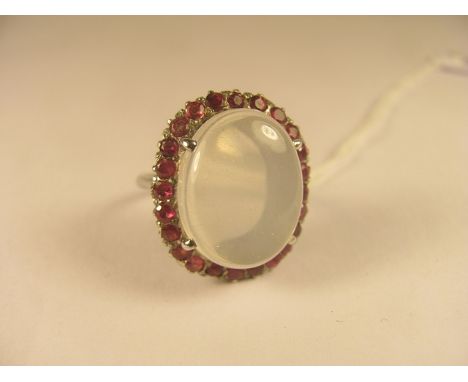 A large white metal oval cabochon moonstone and ruby cluster ring