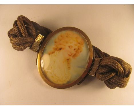 A gold metal framed oval miniature portrait of a woman mounted as a neck collar on a 19th century woven hair bracelet, lock o