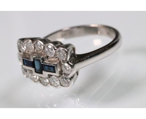 18ct white gold, diamond and sapphire cluster ring. The ring being set with three rectangular step cut sapphires surrounded b