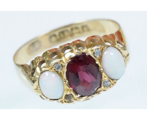 18ct gold garnet and opal three stone ring. The ring being set with a oval mixed cut garnet to centre flanked by two opal cab