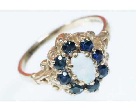 9ct gold opal and sapphire cluster ring. The ring being set with an oval opal cabochon with a halo of round cut sapphires. Ha