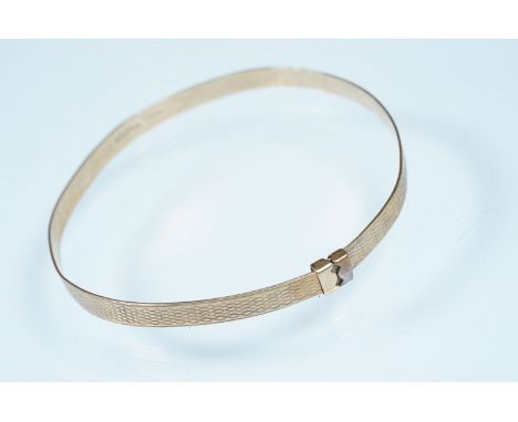 9ct gold engine turned bangle bracelet. Hallmarked Birmingham 1986. Measures 6cm diameter.
