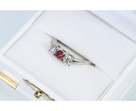 Platinum and diamond three stone ring. The ring being set with a pink diamond to centre flanked by two round brilliant cut di