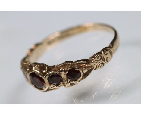 9ct gold and garnet five stone ring. The ring being bezel set with five round cut garnets in a scrolled mount. Hallmarked Lon