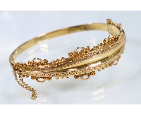 9ct gold bangle bracelet having scrolled details  with hinged opening with tongue in groove clasp. Hallmarked Birmingham, dat