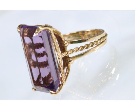 18ct gold and amethyst dress ring being set with a rectangular step cut amethyst to the head in a basket setting with rope tw