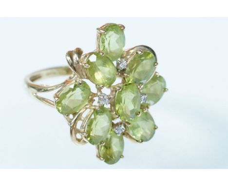 9ct gold peridot and diamond cluster ring. the ring being set with nine oval cut peridot stones with diamond accent stones. H
