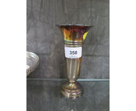 A collection of silver to include a specimen vase, a child's whistle with a mother of pearl handle and a lady's compact 