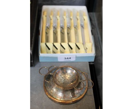 An Arts and Crafts silver plated on copper tea strainer and stand, and six vintage tea knives