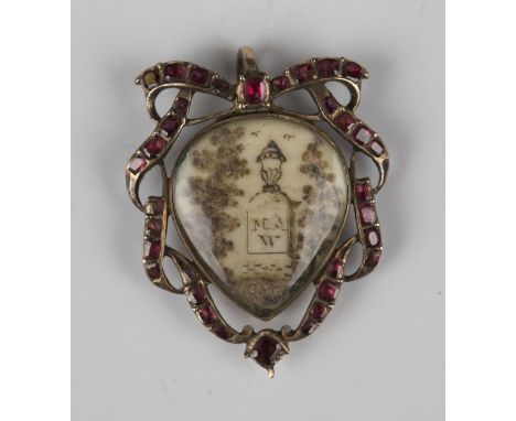 A Georgian gold garnet and hairwork mourning locket, the front glazed with a scene of an urn upon a plinth flanked by two tre