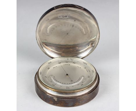 An Edwardian silver cased desk barometer, the silvered dial with mercury thermometer, the cylindrical case with hinged lid, l