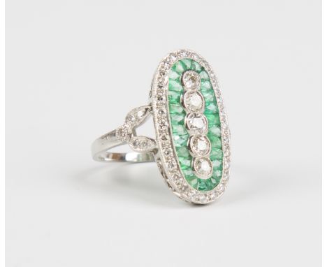 A platinum, emerald and diamond oval panel shaped cluster ring, collet set with a graduated row of five circular cut diamonds