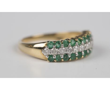 A 9ct gold, emerald and diamond ring, mounted with a row of circular cut diamonds between two rows of circular cut emeralds, 