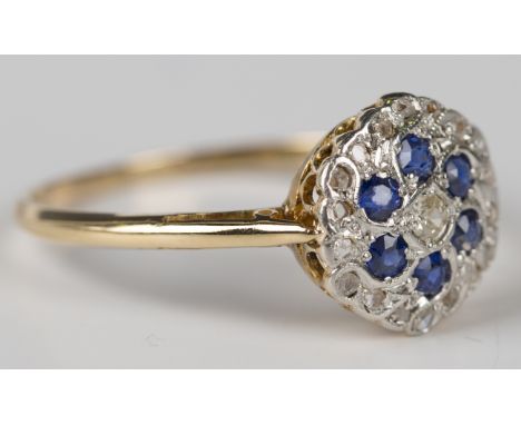 A gold, sapphire and diamond cluster ring, mounted with a cushion cut diamond within a surround of six cushion cut sapphires 