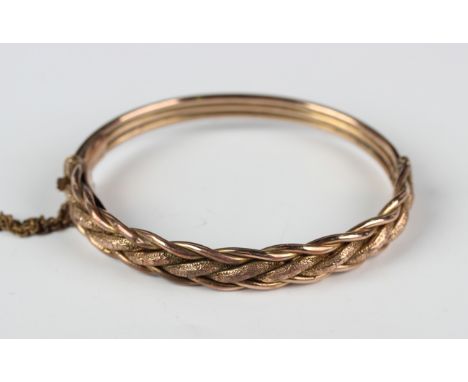 A gold oval hinged bangle, the front in an interwoven design, detailed 9ct', on a snap clasp, weight 9.7g, inside width 5.8cm