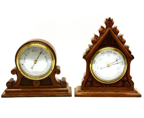 A desktop aneroid barometer in a carved oak case, 27cm high, together with a further similar, both unnamed