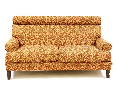 A modern two seater sofa, upholstered in red and cream scrolling foliate fabric, and on turned legs, 160 x 105 x 95cm