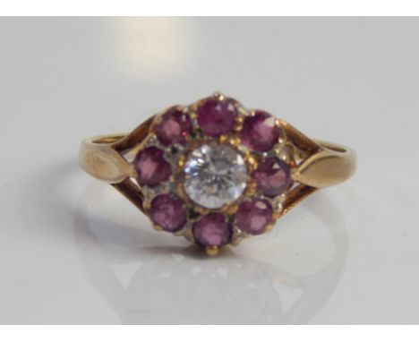 A 9ct gold dress ring, set with garnets and white stone in a floral cluster.