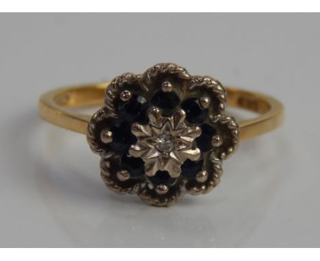 An 18ct gold dress ring, in floral cluster, set with illusion set diamond centre, surrounded by blue stones.