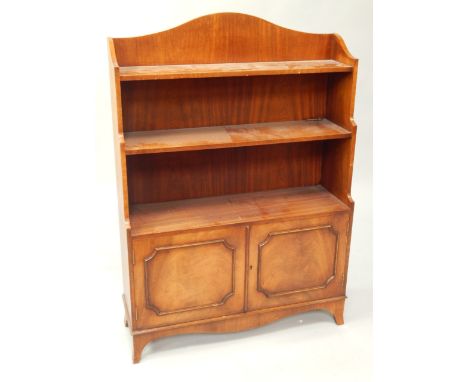 A reproduction mahogany Georgian style waterfall bookcase, with arched gallery top and with a cupboard below enclosed by two 