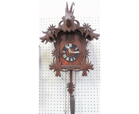 A Black Forest style cuckoo clock, with goats head and a floral scroll carving, 35cm.