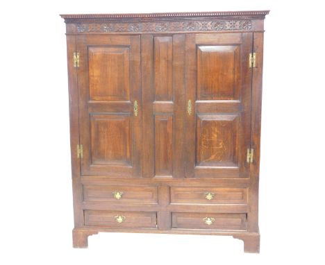 An oak cabinet or wardrobe, in late 17thC style, the top with a moulded cornice above a carved frieze, with an arrangement of