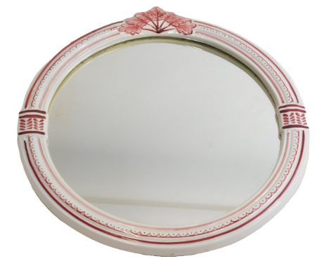 A circular ceramic wall mirror, decorated with red leaves.