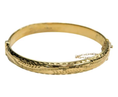 A 9ct gold bangle, with engraved foliate decoration, on a snap clasp, with safety chain as fitted, 8.5g.